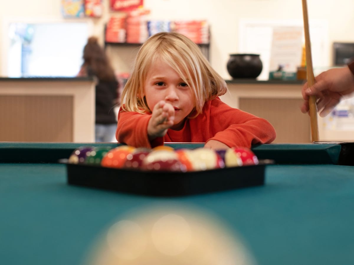 A young child at a pool table
